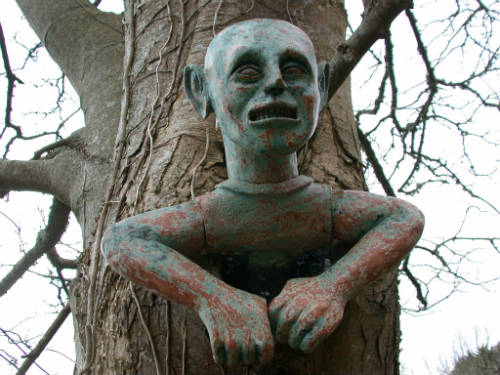 Ceramic sculpture of a spooky man stuck in a tree, by Peter Heywood