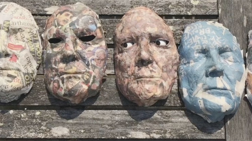 A line of masks, with the eyes moving in one of them